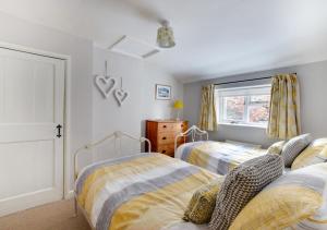 a bedroom with two beds and a window at Angel Cottage in Burnham Market