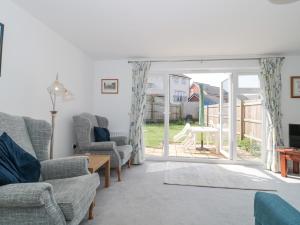 a living room with chairs and a sliding glass door at Covert Cottage in Axminster