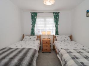 two twin beds in a room with a window at Covert Cottage in Axminster