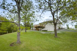 une maison dans un champ avec deux arbres dans l'établissement Cozy Kentucky Retreat - Deck, Near Ark Encounter!, à Dry Ridge