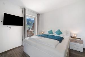 ein weißes Schlafzimmer mit einem großen Bett und einem Fenster in der Unterkunft Haus Tanja Apartment 1 in Partschins