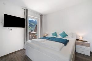 a white bedroom with a large bed and a window at Haus Tanja Apartment 1 in Parcines