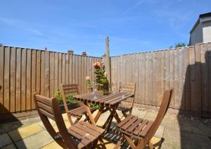 a wooden table and chairs on a patio with a fence at Beachcomber Cottage in Hunstanton