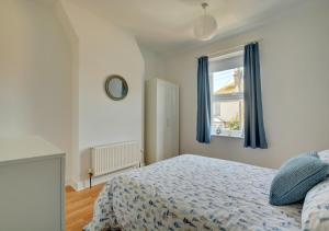 a bedroom with a bed with blue curtains and a window at Beachcomber Cottage in Hunstanton