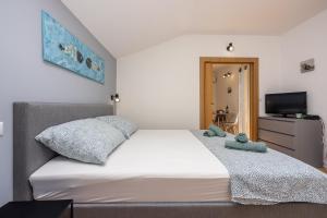 - une chambre avec un lit blanc et une télévision dans l'établissement Apartments Kala, à Crikvenica