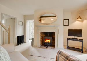 a living room with a fireplace and a tv at Baytree Cottage in Melton Constable