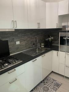 a kitchen with white cabinets and a sink and a stove at Casa Levante Fregene, mare e relax vicino Roma in Fregene