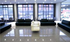 una sala de espera con sofás, sillas y ventanas en NH La Avanzada en Leioa