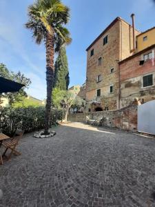 una palmera en un patio con un edificio en Casa di Alice nel Borgo, en Lajatico