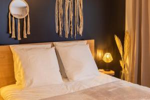 una camera da letto con un letto con cuscini bianchi e uno specchio di Le Nordik Proche Roissy CDG - Paris - Astérix a Dammartin-en-Goële