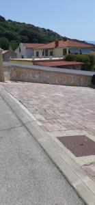 a stone wall next to a sidewalk and a street at Old Town Baska in Baška