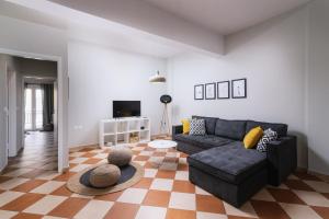 a living room with a black couch and a checkered floor at Hospitium Crete in Moírai