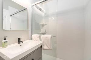 a white bathroom with a sink and a shower at Arrowhead Resort in Saugatuck