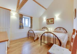 two beds in a bedroom with white walls and wooden floors at Burtons Farm Barn 