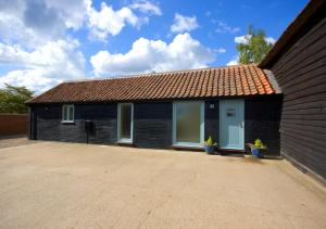 a small black building with two windows and two plants at Burtons Farm Barn 