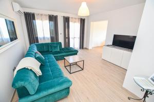 sala de estar con sofá verde y TV en Apartments Palma, en Rovinj