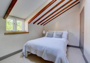 a bedroom with a white bed and a window at Bridge Cottage in North Creake