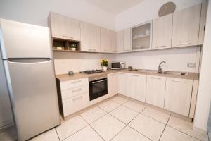 a kitchen with white cabinets and a refrigerator at Sunset home Baia Blu in Gallipoli