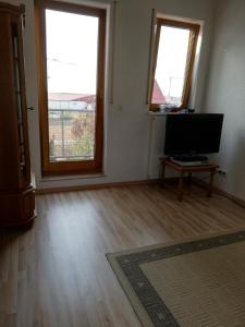 an empty living room with two windows and a flat screen tv at Sonniges Fleckchen in Griesheim