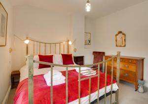 a bedroom with a large bed with red pillows at Brook Cottage in Dersingham