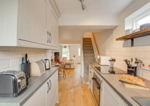 a kitchen with white cabinets and a counter top at Brook Cottage in Dersingham