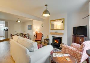 a living room with a white couch and a fireplace at Brook Cottage in Dersingham