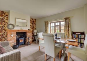 a living room with a table and a fireplace at Carrstone Cottage in Grimston