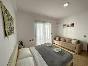 a white bedroom with a bed and a couch at Despacito Port Side in Vlorë