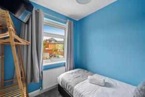 a blue room with a bed and a window at Luxnightzz - Central 3 Bed House Parking in Colchester