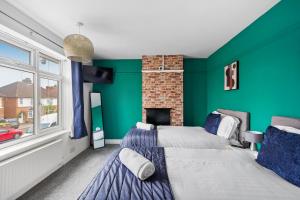 2 camas en una habitación con una pared verde en Luxnightzz - Central 3 Bed House Parking, en Colchester