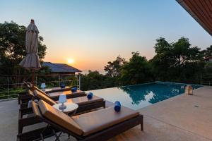 - une piscine avec plusieurs chaises longues et un parasol dans l'établissement Villa Wassana - Sunset View 5Bed, à Koh Samui 