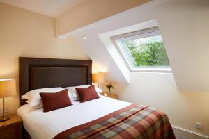 a bedroom with a large bed with a window at Macdonald Elmers Court Resort in Lymington