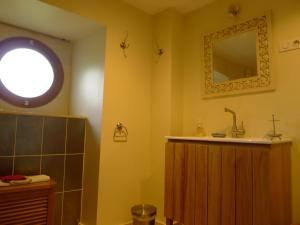 ein Bad mit einem Waschbecken und einem Wandspiegel in der Unterkunft gîte de la Cabotte in Bussy-le-Grand