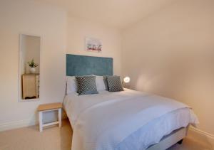 Un dormitorio con una gran cama blanca y una mesa en Corner Cottage en Cromer
