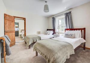 a bedroom with two beds and a mirror at Cuckoo Cottage in Blakeney