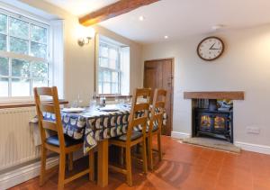 a dining room with a table and chairs and a clock at Cuckoo Cottage in Blakeney