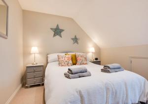 a bedroom with a large white bed with two pillows at Curlew Cottage in Wells next the Sea