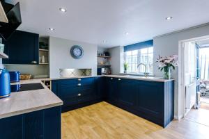 a kitchen with navy blue cabinets and a sink at Cheshire Countryside, Delamere Forest, Family Retreat Rose Cottage in Kelsall