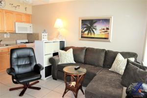 a living room with a couch and a chair and a kitchen at Tropic Breeze 17 in St. Pete Beach