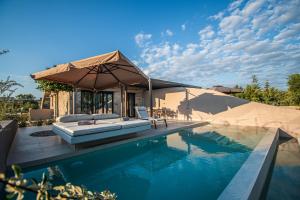 a house with a swimming pool and an umbrella at Nestor Luxury Villas with Private Pools in Romanós
