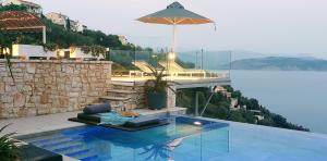 a swimming pool with an umbrella next to the water at Aquamarine Villa in Agní