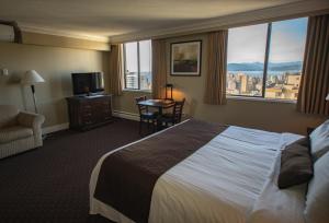 Century Plaza Hotel في فانكوفر: غرفة فندقية بسرير كبير ونافذة