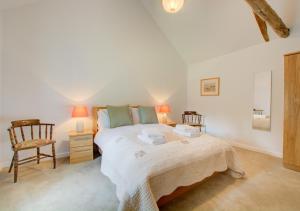 a bedroom with a large bed and two chairs at Dockings Cottage in Hindringham