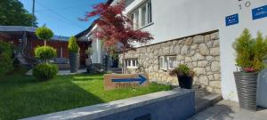 a house with a stone wall and a sign in the grass at Apartmani Remete in Zagreb