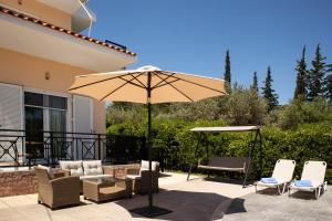 Un patio con sombrilla y sillas y una mesa. en Villa George Rhodes, en Archangelos