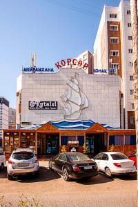 budynek z samochodami zaparkowanymi przed nim w obiekcie KORSAR w mieście Astana