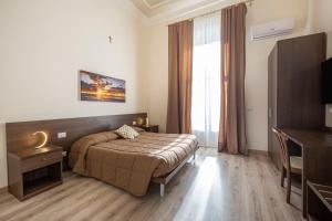 Habitación de hotel con cama y TV en B&B Ambitious en Catania