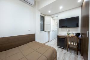 a bedroom with a bed and a desk and a television at B&B Ambitious in Catania