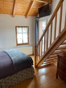 ein Schlafzimmer mit einem Bett und eine Treppe mit einem TV in der Unterkunft Chambres d’hôtes plateau des mille étangs 