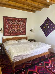 - une chambre avec un lit et un tapis sur le mur dans l'établissement Hotel Legende, à Samarcande